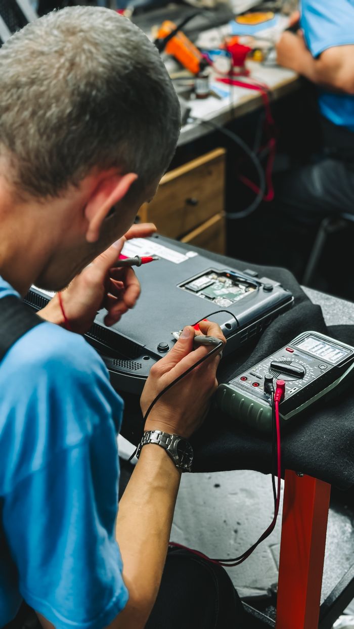 creative-03 Professional technician repairing an electronic device with precision tools and a multimeter.