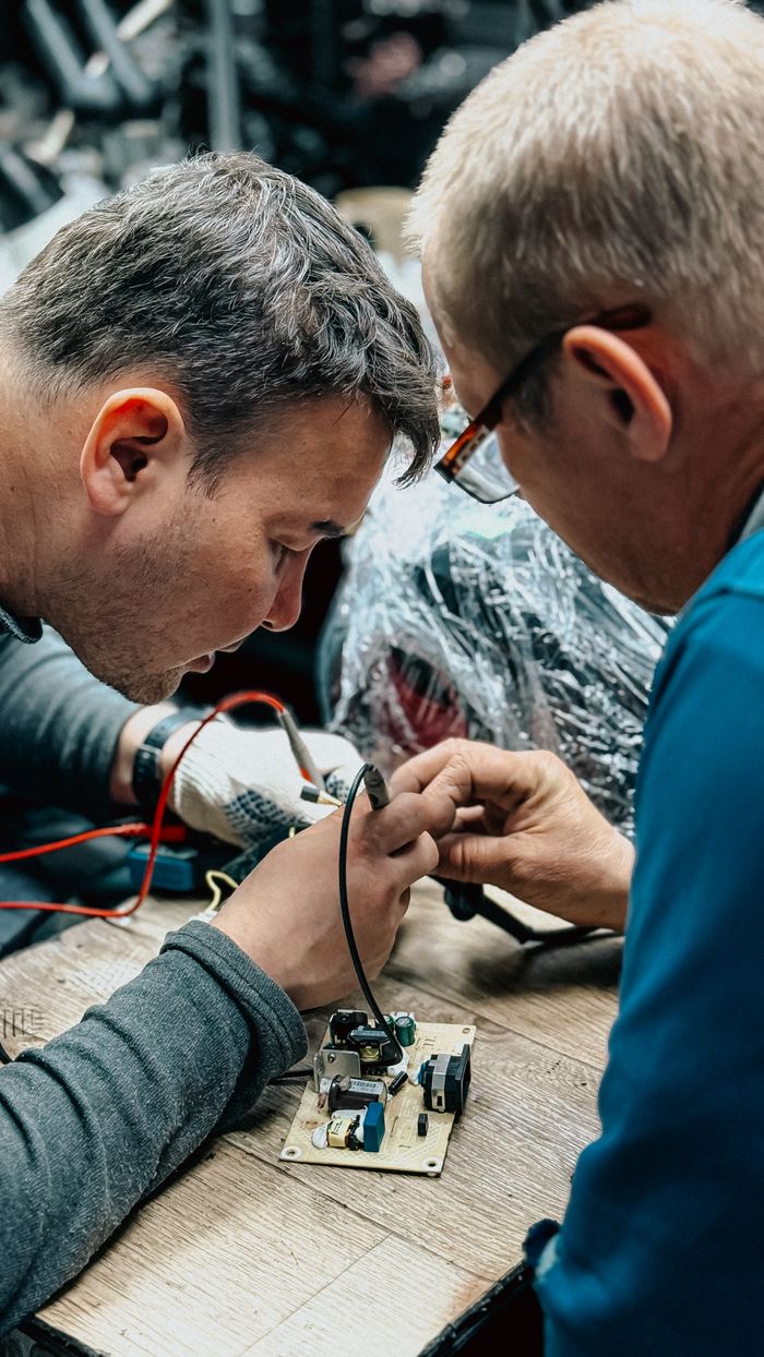 creative Focused technicians meticulously repair a circuit board in a workshop.
